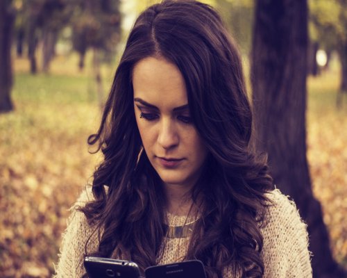Commuter looking at phone while holding onto handrail